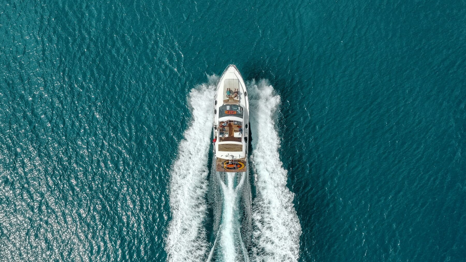 Desert Wind under way, throwing a long white wake across open blue water